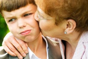 grandmother kissing a reluctant grandson on the cheek