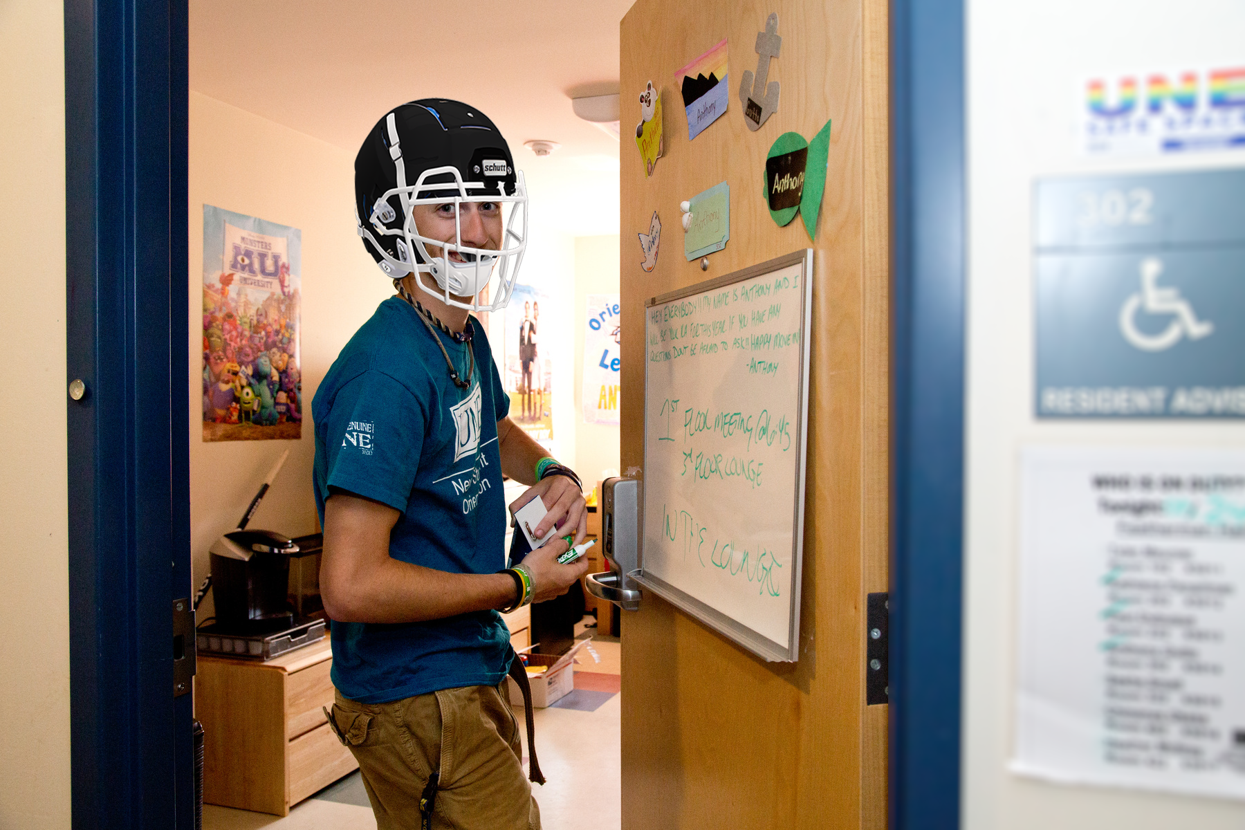 An RA in a dorm room wearing a football helmet