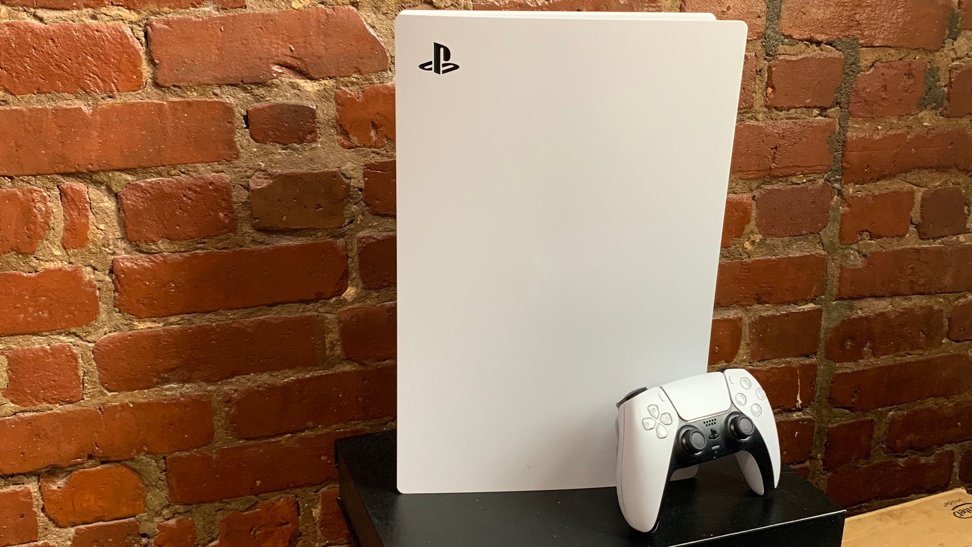 ps5 gaming console in front of a brick wall