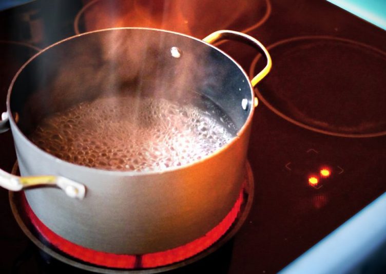 a pot on a stove, bubbles and steam rising