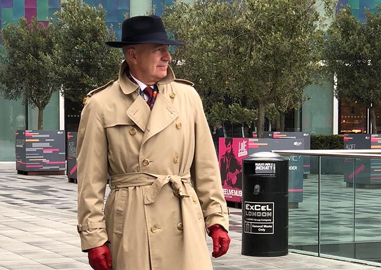A conspicuous looking man in a hat and tan trench coat.