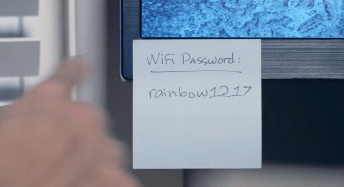 A sticky note stuck to a computer reading "Wifi Password: rainbow1217"