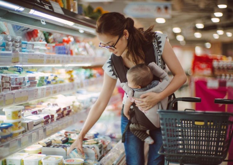 A woman at the grocery store with a baby.