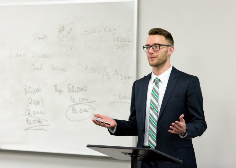 A pretentious looking man standing in front of a whiteboard