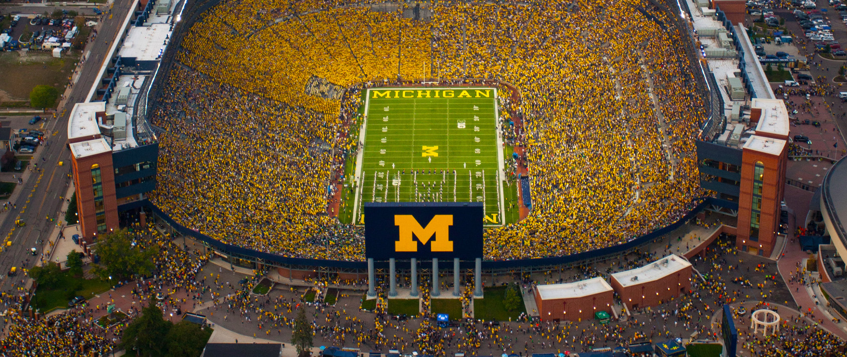Overhead shot of a very filled Big House at night. Michigan logo is visible
