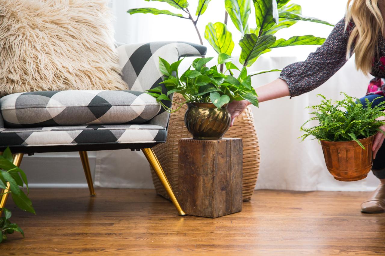 Woman setting up potted fake plant in living room