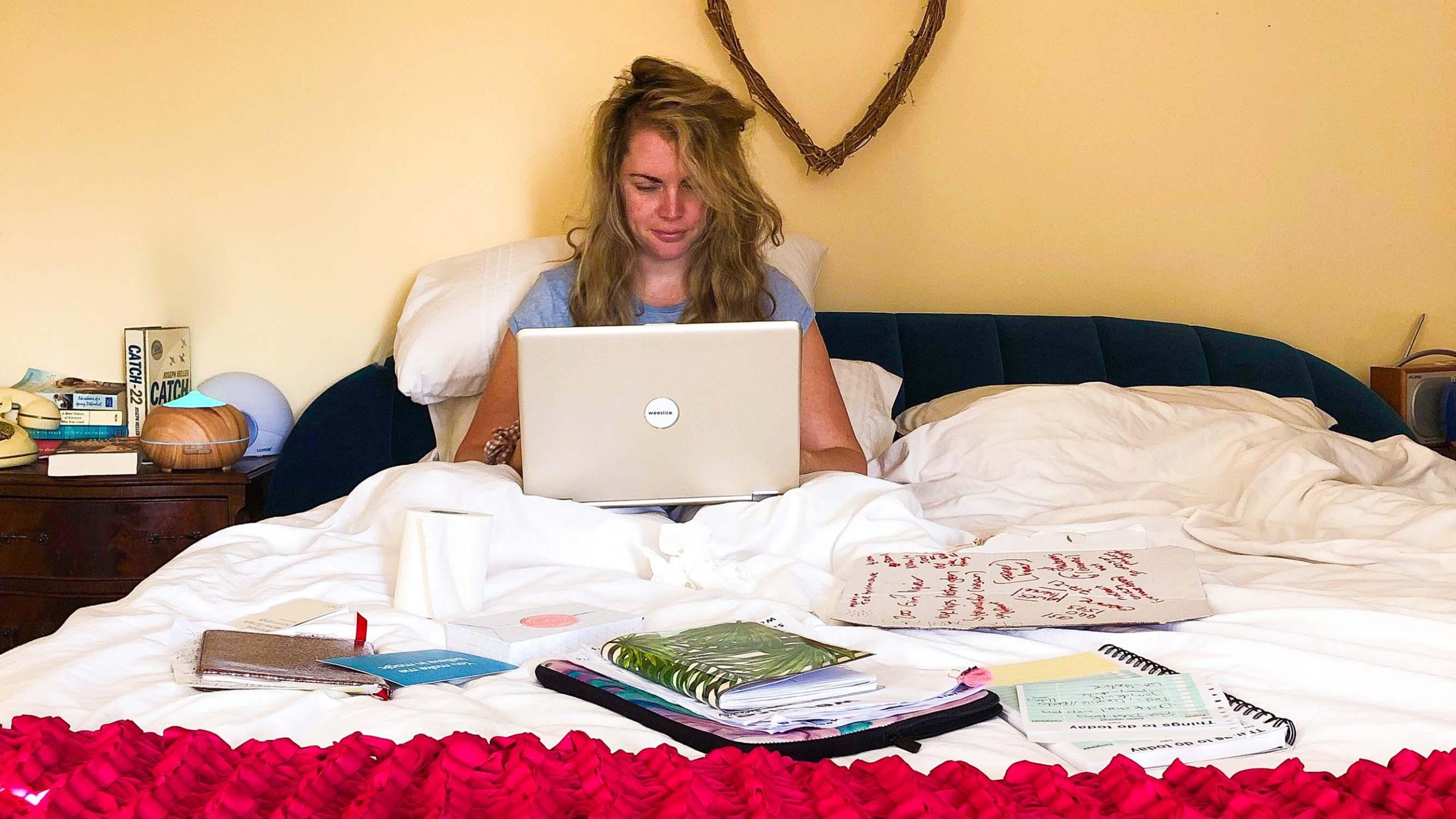 Sickly, sad woman sitting in bed with laptop on lap