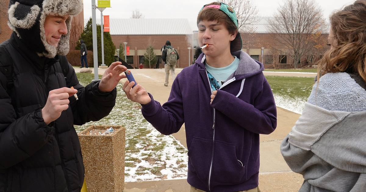 Student with cigarette in mouth exchanging a lighter