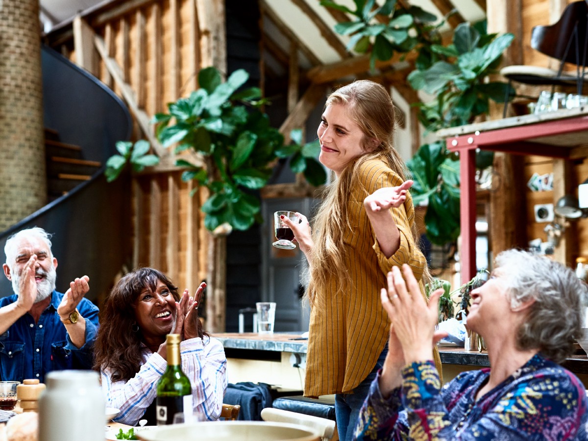 A woman is shrugging at a lunch while some older people are clapping?