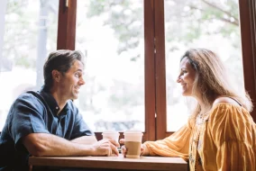 Man and woman holding coffees, chatting