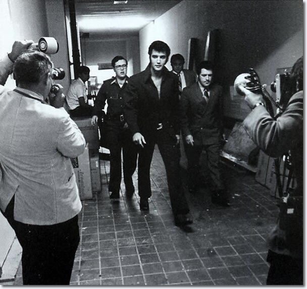 Vintage black-and-white photo of Elvis walking, surrounded by paparazzi