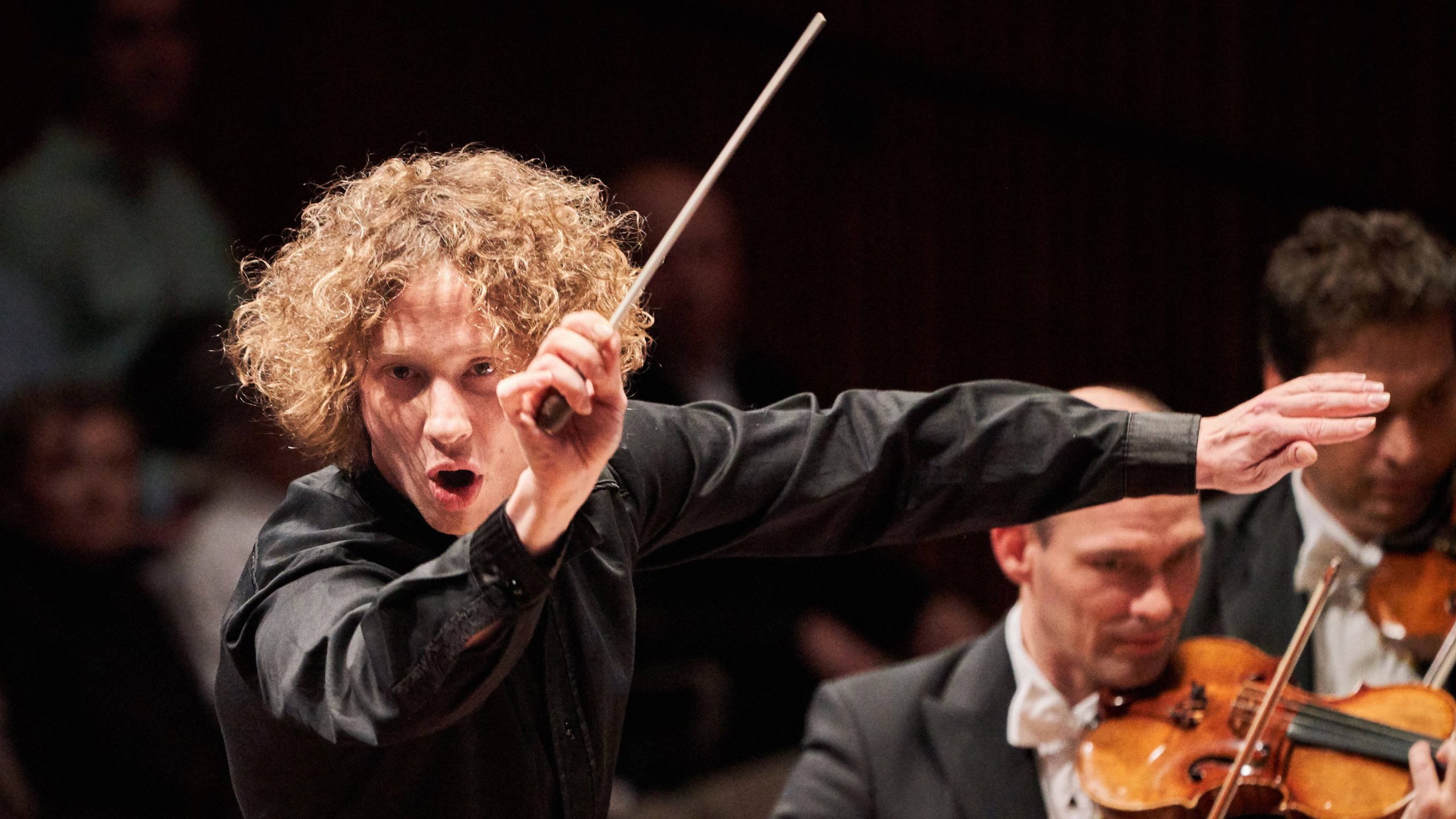 Conductor with long hair, mouth open