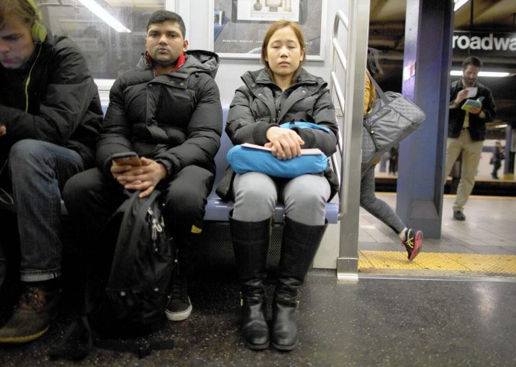 Two people sitting next to each other on a subway