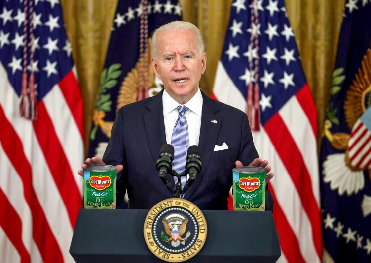 President Biden standing at a podium with several cans of green beans