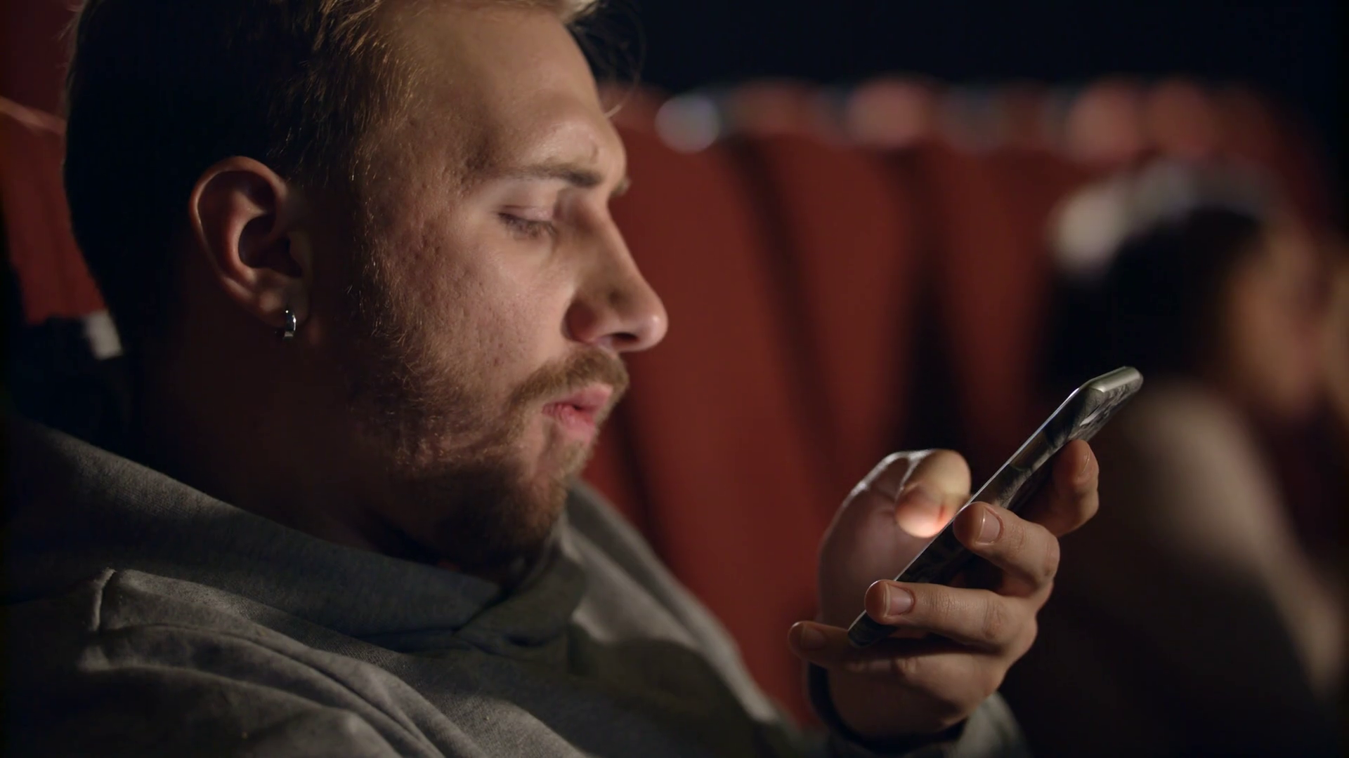 Man sitting alone checking his phone before his movie begins