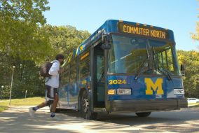 Student walking onto blue bus reading "Commuter North"