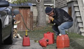 A man siphoning gas from a car.