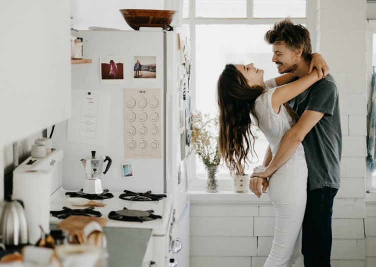 Picture of a couple romantically hugging in a sunlit kitchen