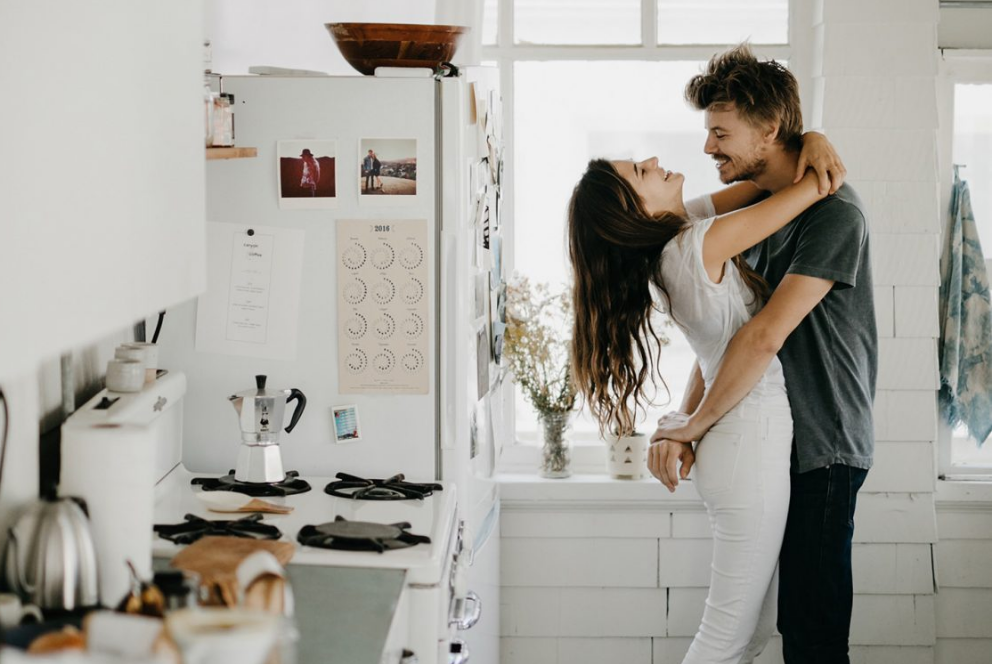 Picture of a couple romantically hugging in a sunlit kitchen