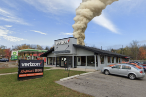 Photoshopped smoke on coming from building with sign in front saying "Verizon" and "Satchel's BBQ"