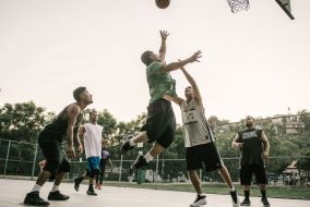 Men playing basketball in a park.
