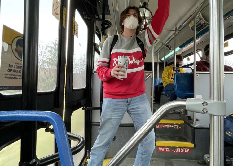 Man standing, holding handle inside of bus