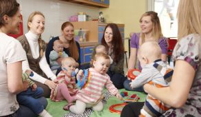 A group of mothers are playing with their children in a classroom