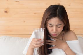 Picture of a woman apparently choking and attempting to drink a glass of water.