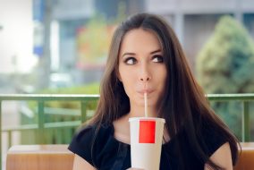 Portrait of a funny girl drinking trough a straw