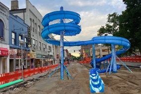 A waterslide constructed on a dirt-paved state street.