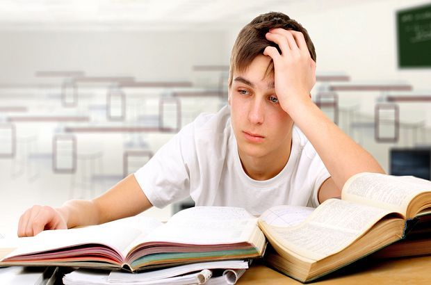 A boy with his head in his hands frustrated with studying.