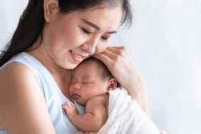 A woman hold a newborn baby to her chest.
