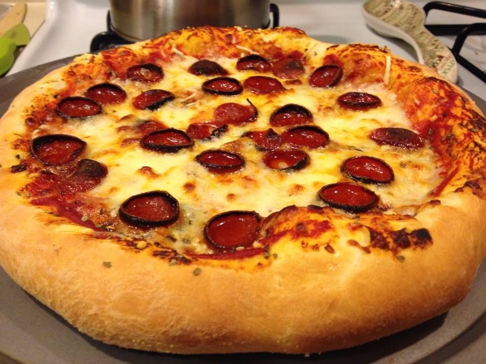 A thick-crusted pepperoni pizza sits on a baking sheet.