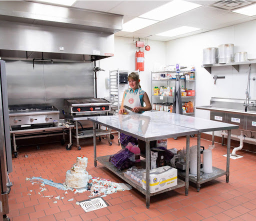 A young girl in a kitchen next to a spilled cake on the floor