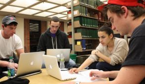 Students sitting at a table in a library working in a group project