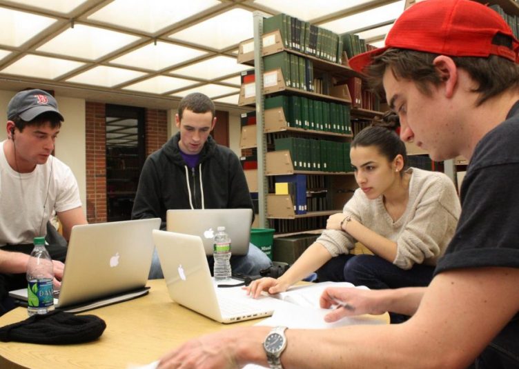 Students sitting at a table in a library working in a group project
