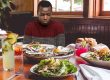 A man frowns at a restaurant table full of food.