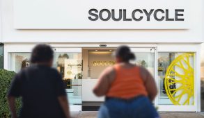 Two people sit outside a Soulcycle on a bench