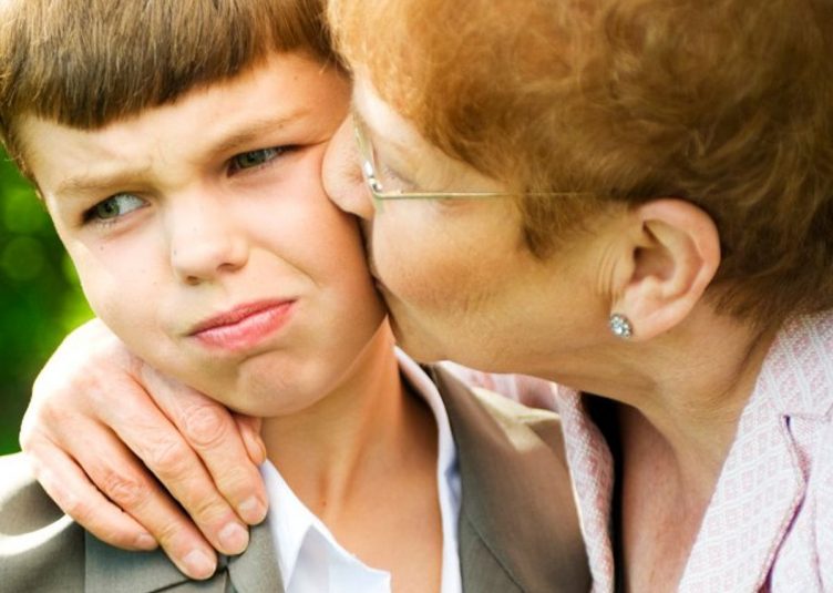 grandmother kissing a reluctant grandson on the cheek