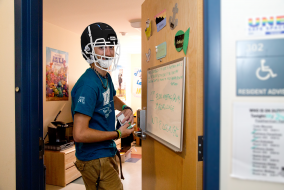An RA in a dorm room wearing a football helmet