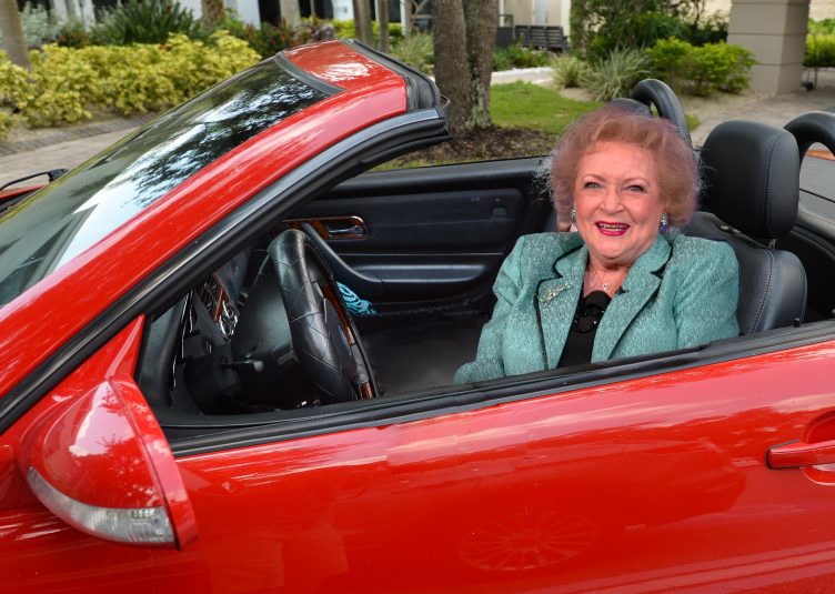 A very self-satisfied looking Betty White sitting in a red Ferrari.