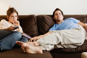 Bored man and woman lounging on couch