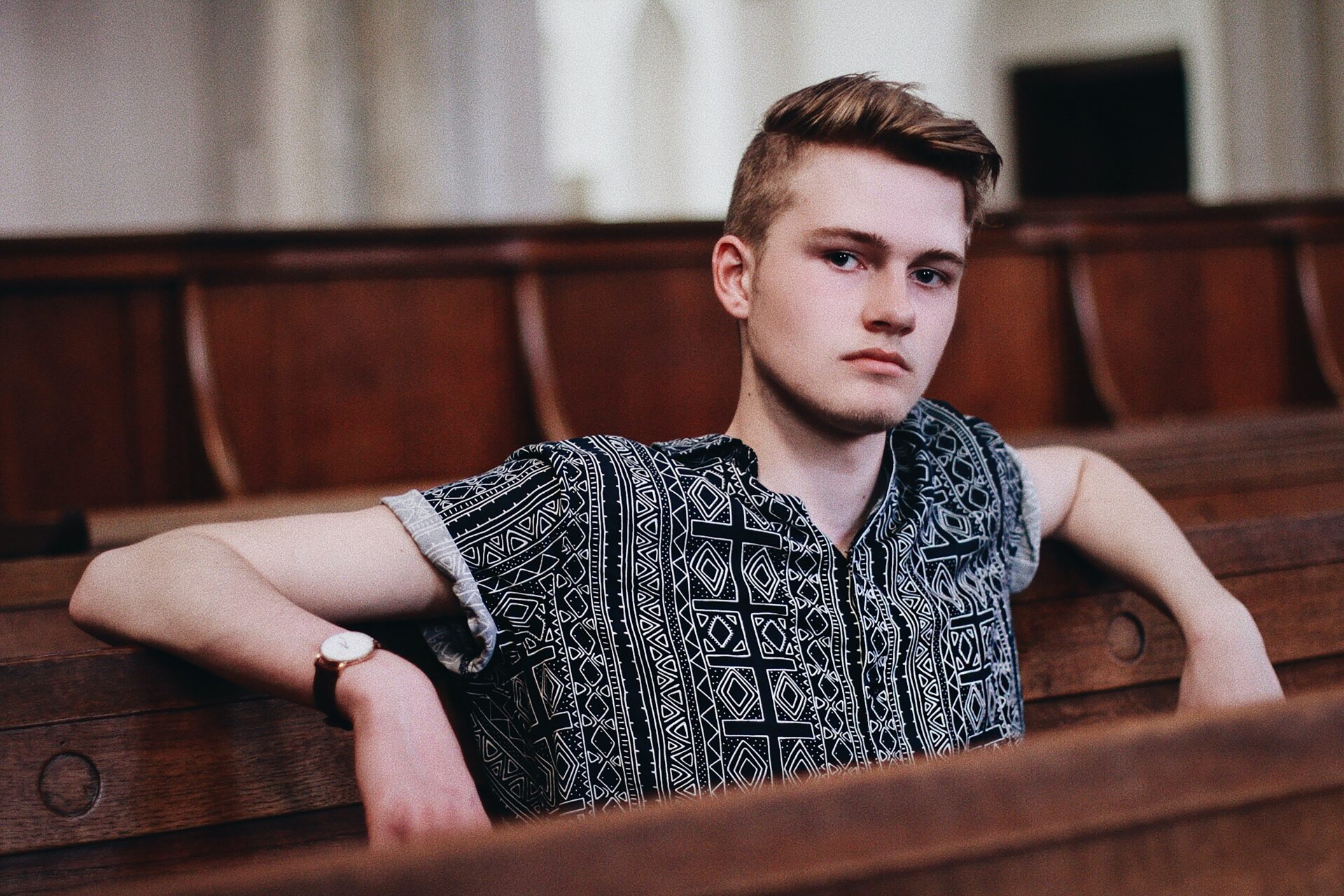 A young man on a church pew with a sour look on his face