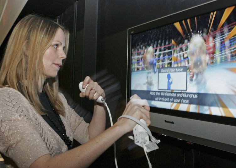A woman uses a wireless controller to play a boxing game on a Nintendo Wii