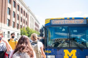Several students are walking towards a Campus Connector bus.
