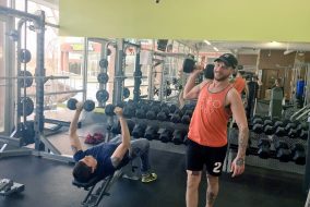 Two men lifting weights in gym and one man is really excited