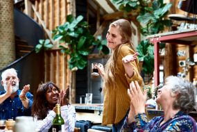A woman is shrugging at a lunch while some older people are clapping?