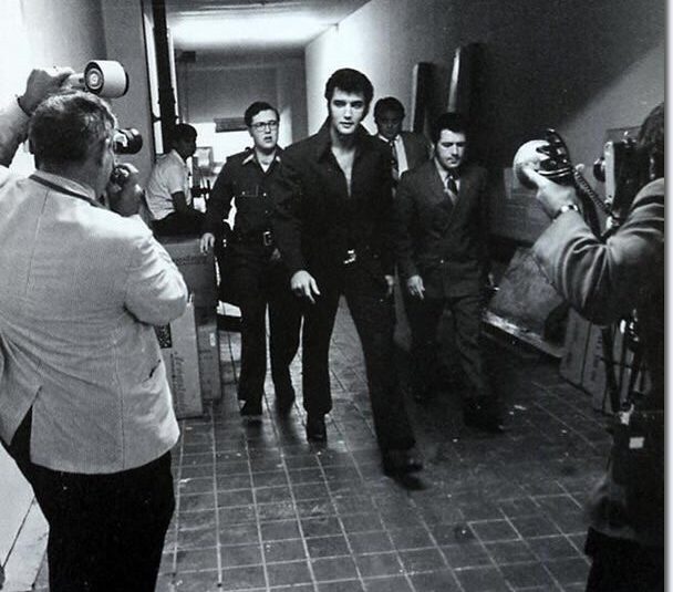 Vintage black-and-white photo of Elvis walking, surrounded by paparazzi