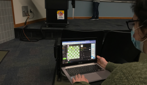 A student playing chess in the front row of a lecture.