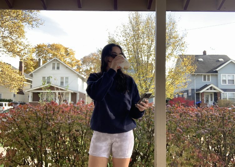 Woman dressed in dark sweatshirt and white, mid-length shorts